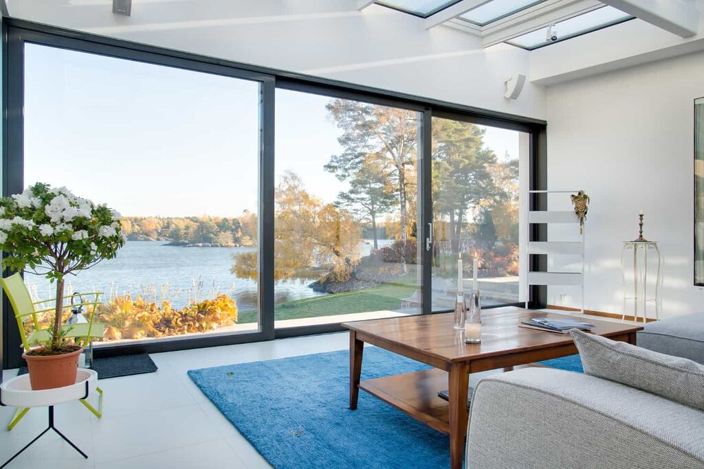 séjour d'une maison moderne avec une grande baie vitrée qui donne une belle vue sur un lac 